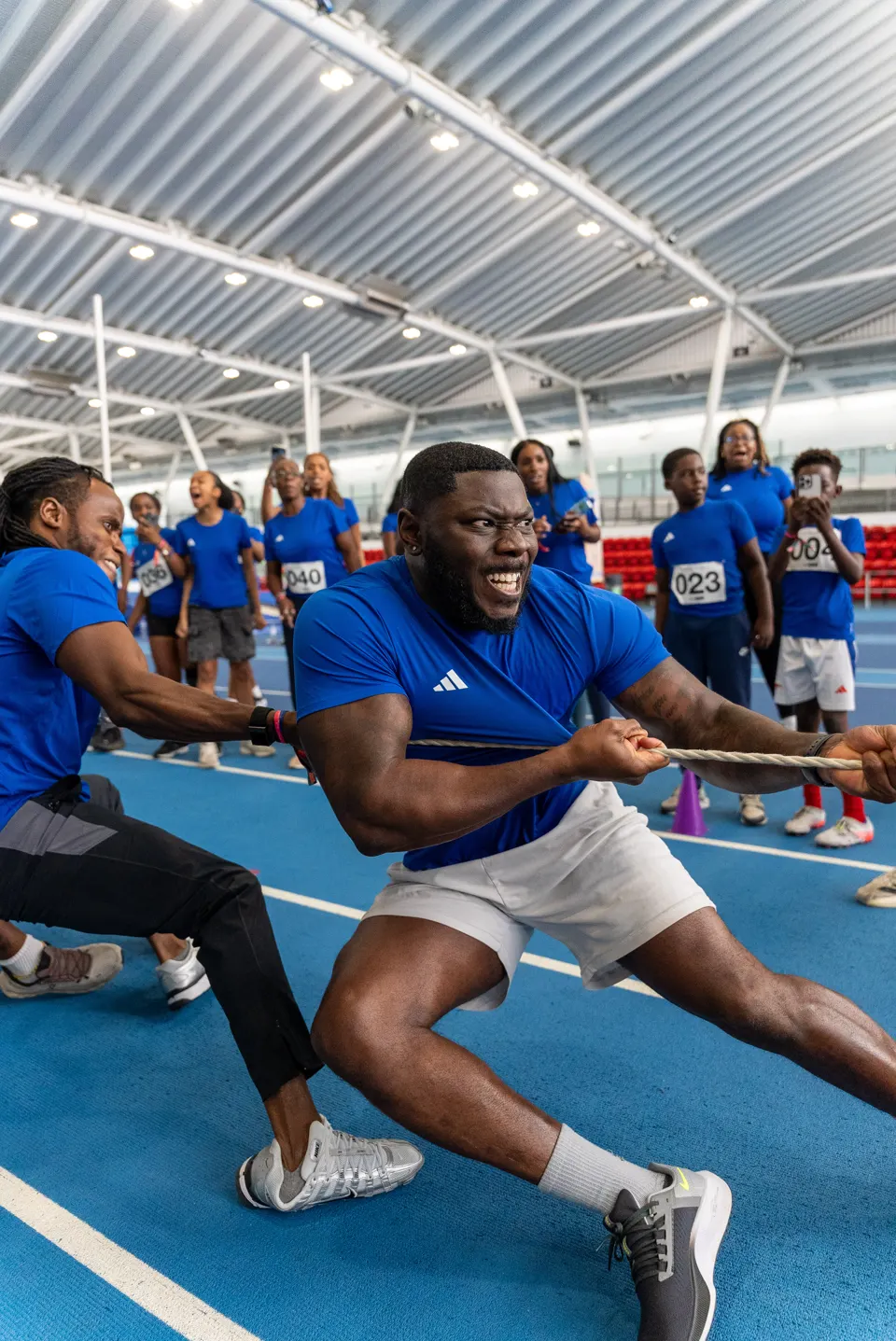 Members pulling hard in a tug-of-war contest on an indoor running track