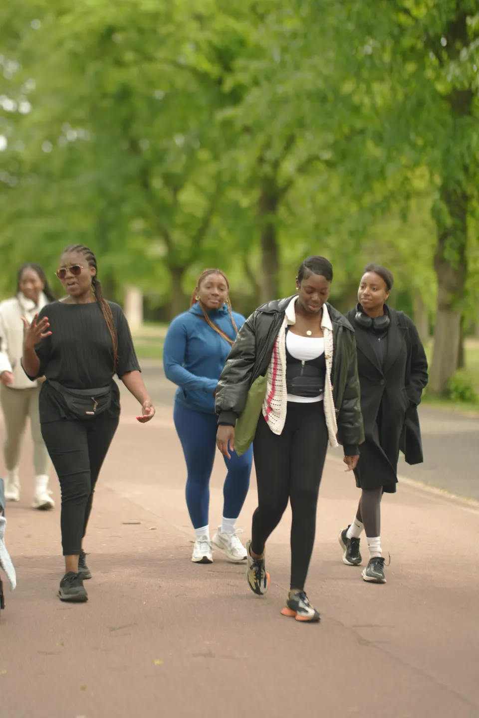 A mixed group of members walking toward the camera under the trees